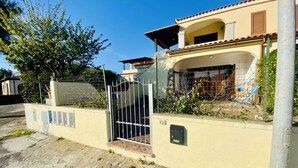 Una propietat residencial amb entrada tancada per reixa, un porxo cobert i un camí d'accés pavimentat amb pedra.