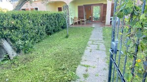 Un jardin bien entretenu, avec un chemin pavé menant à un bâtiment doté d’un patio couvert.