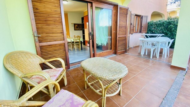 Un espace extérieur aménagé avec des meubles en osier, une table et une chaise.