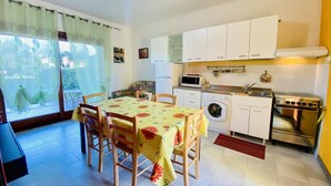 Une cuisine compacte avec des meubles blancs, un lave-linge, un four à micro-ondes et une cuisinière.