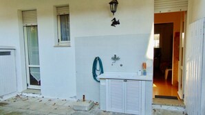 A white building with a small outdoor sink, a hose, and a door leading inside. - M282 - Marcelli, three-room apartment with garden 100m from the sea (Marcelli)
