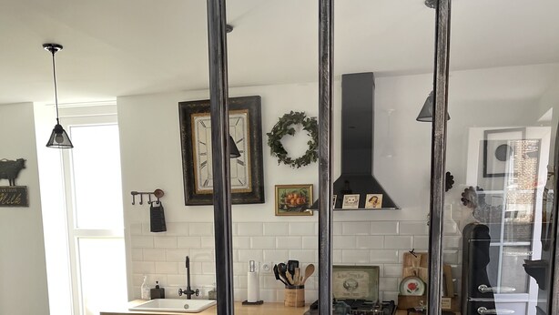 Eine moderne Küche mit großem Fenster, dunklen Schränken und einem sichtbaren Herd.