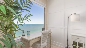 Ein Zimmer mit Schreibtisch, Stuhl und Meerblick.