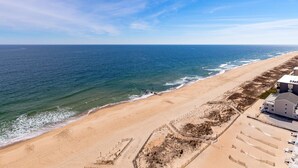 Ein Strand mit blauem Himmel, sandigem Ufer und einem Gebäude mit flachem Dach.