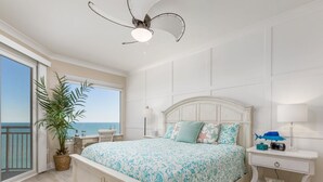 Ein Schlafzimmer mit einem großen Bett, einem Nachttisch, einer Lampe und Blick aufs Meer.