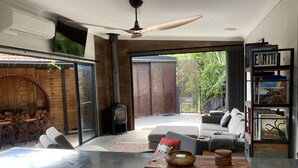 A modern living room with a fireplace, seating area, and a bookshelf. - thespaceperth- the funkiest bali style villa in Perth (Maida Vale)
