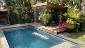 A rectangular swimming pool with a wooden deck and a built-in bench. - thespaceperth- the funkiest bali style villa in Perth (Maida Vale)