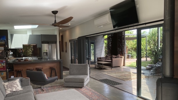 A modern living room with a grey sofa, a coffee table, and a TV mounted on the wall. - thespaceperth- the funkiest bali style villa in Perth (Maida Vale)
