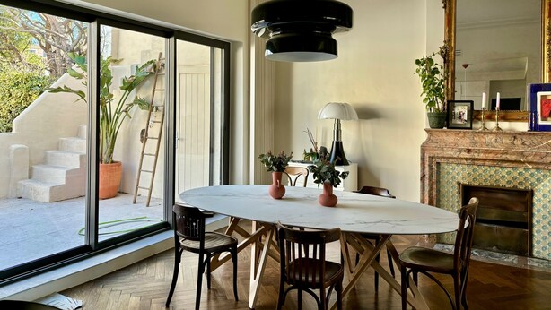 A dining area with a round table, chairs, a chandelier, a fireplace, and a large mirror. - House facing the sea, bright, air-conditioned, terrace, family, calanques (Marseille)