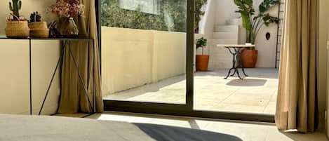Une chambre avec une grande porte-fenêtre coulissante donnant sur une terrasse extérieure.