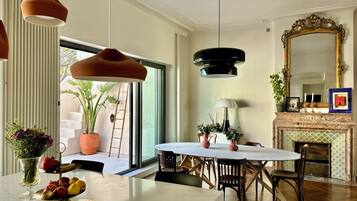 A dining area with a marble table, wooden chairs, pendant lighting, a fireplace, and a large mirror.