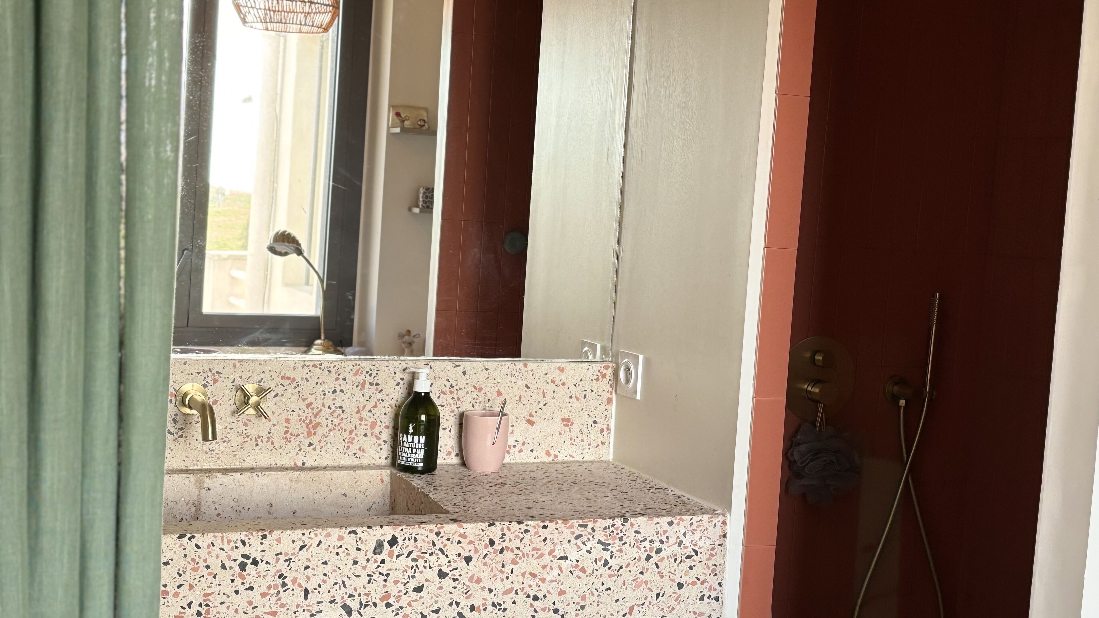 A bathroom with a sink, mirror, and shower.