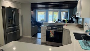 A modern kitchen with a built-in oven, a refrigerator, and a dining area with a view of the outdoors.