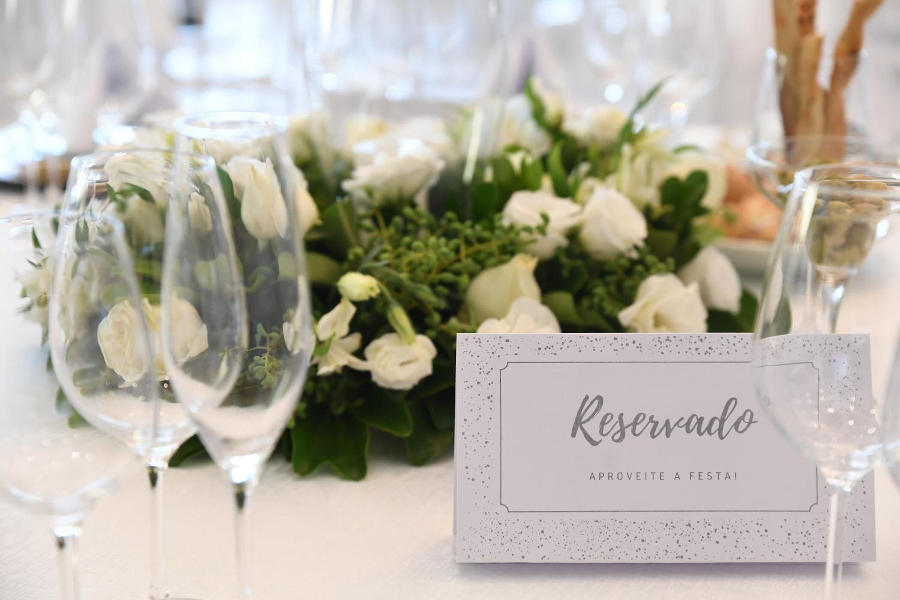 A table setting with a 'Reserved' sign, clear glassware, and a floral arrangement.