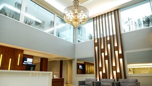 A spacious lobby with a reception desk, comfortable seating, a large chandelier, and a high ceiling with natural light. - Hotel Alvorada (Concordia)