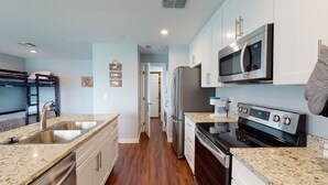 Una cocina moderna con encimeras de granito, electrodomésticos de acero inoxidable y una isla central.