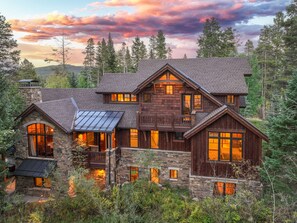 A large, multi-story log cabin with a stone foundation, multiple windows, and a balcony. - Bear Tracks Lodge: Private Hot Tub, Steam Room, Theater & Pool Table (Breckenridge)