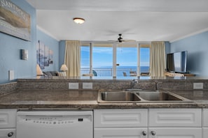 A kitchen with granite countertops, a dishwasher, and a view of the ocean.