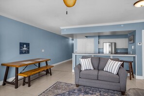 A living room with a gray sofa, wooden bench, and a blue rug.