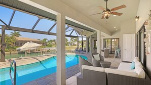 A covered outdoor swimming pool area with lounge seating and a ceiling fan. - Stunning Home | Pool, Dock & Direct Gulf Access (Marco Island)