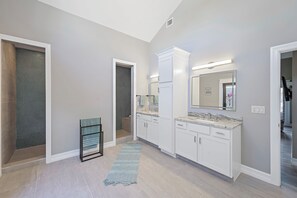 A modern bathroom with a walk-in shower, a vanity with a marble countertop, and a large mirror above the sink. - Stunning Home | Pool, Dock & Direct Gulf Access (Marco Island)
