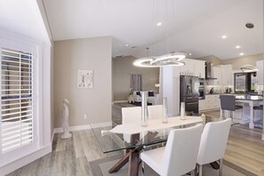 Une cuisine moderne avec des meubles blancs, un îlot central et des luminaires suspendus.