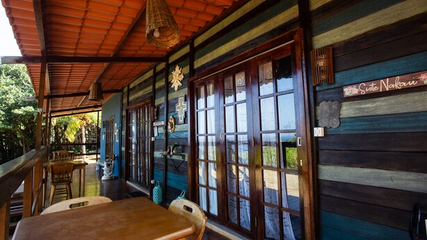 A wooden cabin with a covered porch, large windows, and a sign reading "Suite Nakai". - Pousada Vila Nakau (Fernando de Noronha)