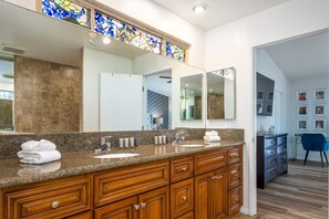 A bathroom with a granite countertop, wooden cabinets, a large mirror, and a stained glass window above the mirror. - Risky Business – Retro Cool Palm Springs (Palm Springs)