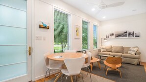 Una habitación moderna con una mesa redonda, sillas blancas, un sofá y un ventilador de techo.