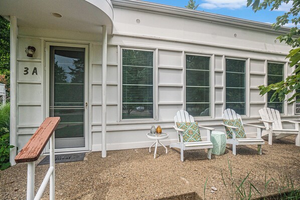 A house with a number '3A' on the door, a porch with three Adirondack chairs, a small table, and a potted plant. - 🏖️Sleepy Hollow Beach Resort, Cottage 3A – Family Fun on Lake Michigan! (South Haven)