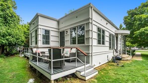 A two-story house with a deck, large windows, and a covered porch area. - Sleepy Hollow Beach Resort, Cottage 3C – Family Fun on Lake Michigan! (South Haven)