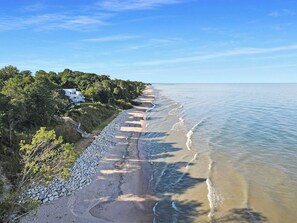 Una propiedad costera con un paseo pavimentado a lo largo de la playa, un muro de piedra y una casa con vista al mar.