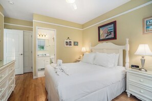 Une chambre à coucher bien rangée, avec un grand lit, des tables de chevet, une commode et un miroir.