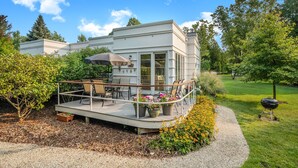 Una casa moderna con terraza, mobiliario exterior y una parrilla.