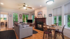 Amplia sala de estar con chimenea, televisor y comedor con sillas de madera.