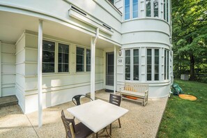 A white building with a covered patio area featuring a table and chairs, a bench, and a number '50' sign. - 🏖️Sleepy Hollow Beach Resort, Gateway 50 – Family Fun on Lake Michigan! (South Haven)