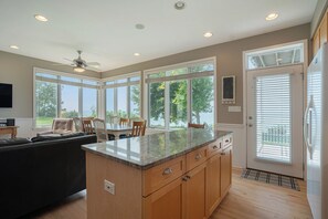 Una cocina moderna con una isla grande, armarios de madera y un comedor con sillas y una mesa.