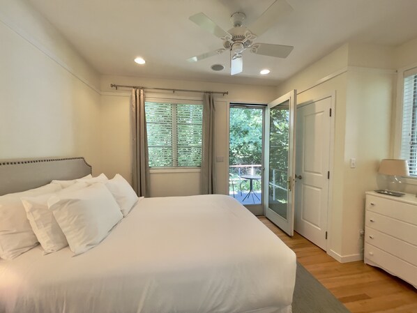 A bedroom with a large bed, a ceiling fan, and a sliding glass door leading to an outdoor area.