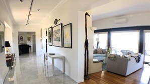 Ein geräumiger Wohnbereich mit Marmorboden, einem weißen Sofa, einem Couchtisch und einem großen Fenster, das für natürliches Licht sorgt.