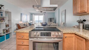 Une cuisine moderne dotée d’une cuisinière, d’un four et d’un four à micro-ondes en acier inoxydable, de meubles de rangement en bois et d’un comptoir en granit.