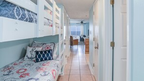 Une chambre avec des lits superposés, un bureau et une vue sur l’océan.