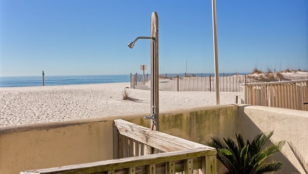 Une vue sur la plage avec une clôture en bois, un mur en béton et une structure métallique.