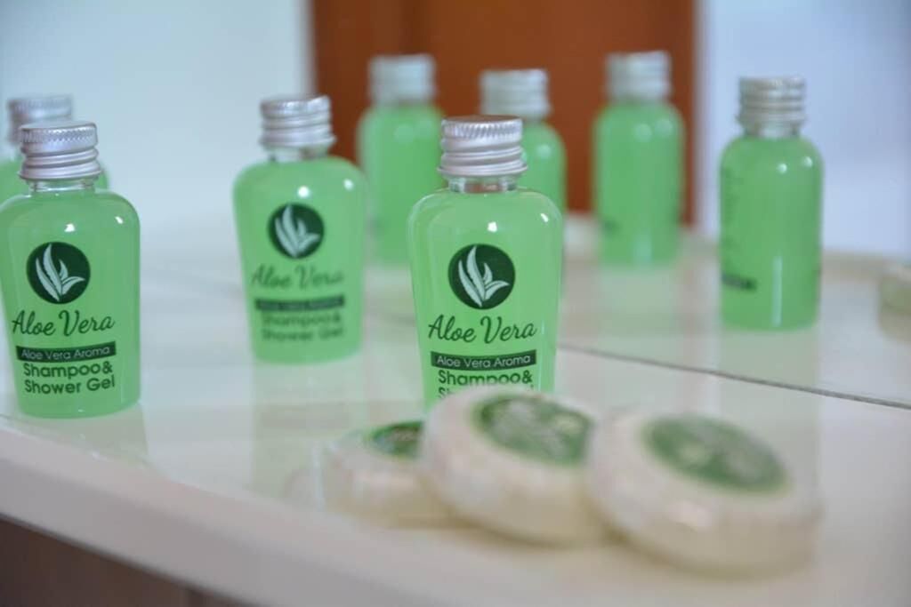 Eine Anordnung aus grünen Flaschen, beschriftet mit 'Aloe Vera Shampoo & Shower Gel', auf einer weißen Oberfläche.