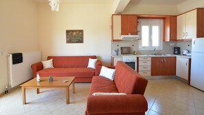 A compact living area with a sofa, a coffee table, and a kitchenette. - Olive Oil Residence (Hersonissos)