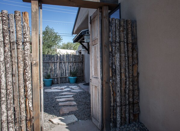 A wooden gate leading to a gravel path with potted plants.