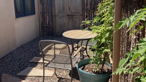 Eine Terrasse mit Tisch und Stühlen, einem Blumentopf und einem hölzernen Gartentor.