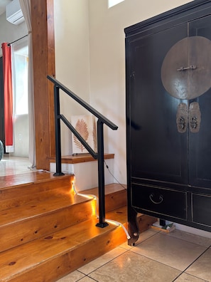 A staircase with wooden steps and a metal handrail, leading to a black cabinet with two doors.