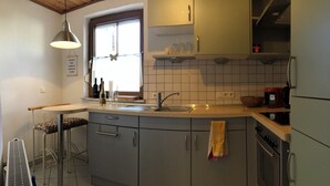 Cocina pequeña con fregadero, estufa y ventana.