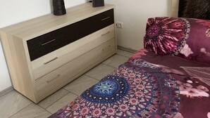 Un dormitorio con cama, mesita de noche, lámpara y cómoda.