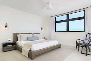 Ein modernes Schlafzimmer mit einem großen Bett, Nachttischen, einem Sessel und einem Fenster mit Blick.